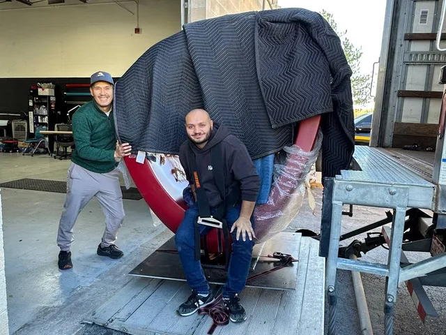 Sun City Moving crew members securing a large wrapped item on a truck ramp