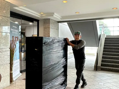 A Sun City Moving crew member delivering a wrapped item through a building lobby