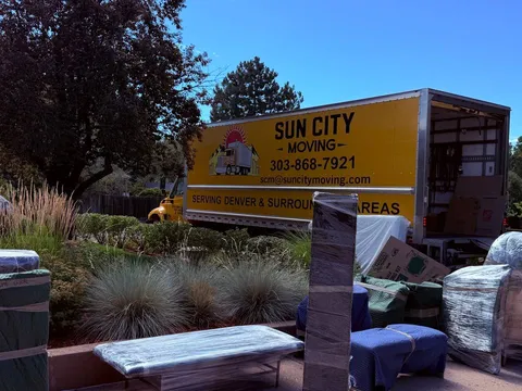 Wrapped furniture staged on a front yard beside a Sun City Moving truck