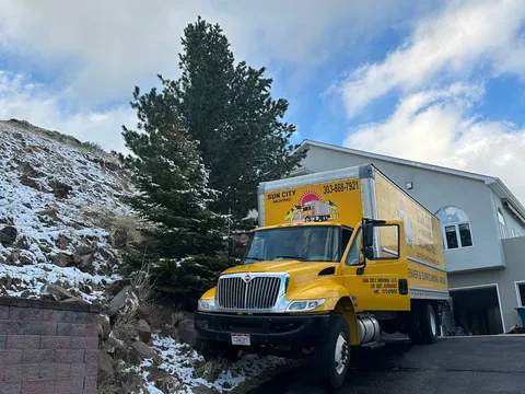 A Sun City Moving truck on a snowy residential driveway