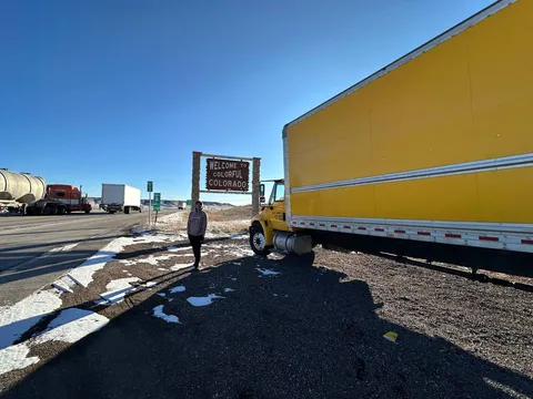 A Sun City Moving truck stopped at the Welcome to Colorful Colorado state-line sign